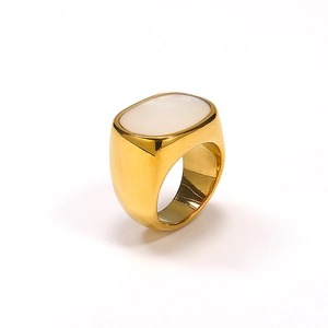 Macro detail of gold signet ring featuring an oval white shell inlay and polished finish