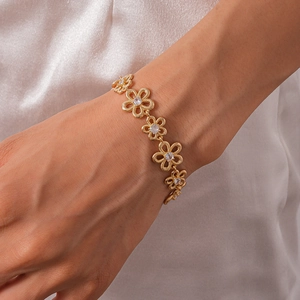 Detail of gold floral bracelet featuring hollow five-petal flowers and white zircon stones