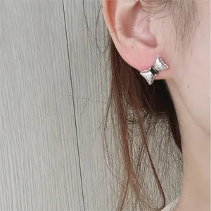 Close-up of minimalist silver bow earrings with black zircon on model for a refined look