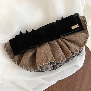Barrette nœud en velours vintage avec étiquette dorée sur fond de tissu blanc
