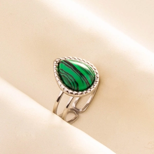 Detailed view of silver open ring with pear-shaped green malachite stone on beige fabric