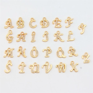Flat lay of 26 golden alloy alphabet pendants with rhinestones for DIY jewelry making