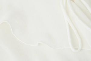 Macro shot of white sheer mesh fabric with ruffle hem and delicate tie detail