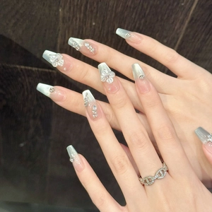 Macro detail of long coffin nails with 3D white floral reliefs and pearl accents