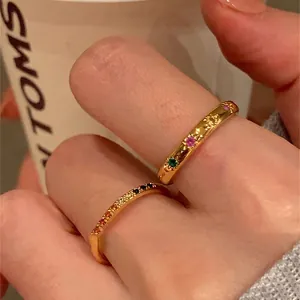 Anelli dorati minimalisti con zirconi colorati e incisione a raggiera sulla mano