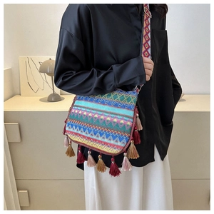 Detailed shot of ethnic woven shoulder bag featuring colorful tassels and wide strap style