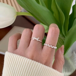 Detail of silver bow and beaded rings worn by a model with white tulip flowers