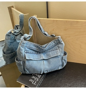 Detailed view of light blue denim crossbody bag featuring large front flap pockets and adjustable strap