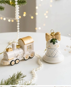 Detail of vintage train and bell Christmas ornaments with white and gold glitter finish