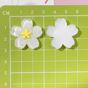 Close-up of translucent cherry blossom resin charms with glitter on a scale mat