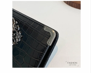 Detail of black crocodile texture leather and silver metal corner on women's long clutch