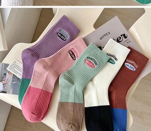 Detail of five pairs of cotton blend crew socks with letter embroidery and ribbed texture