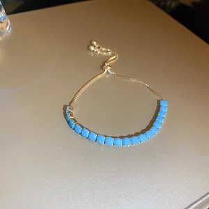 Détail du bracelet doré ajustable avec perles rondes bleu ciel et fermoir coulissant