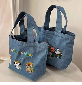 Close-up of Japanese cartoon embroidery on blue denim tote bags showing fine stitch details