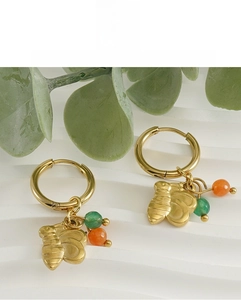 Détail de boucles d'oreilles en acier doré 18 carats avec pendentifs abeille et pierres