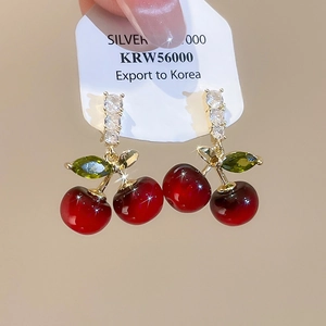 Gros plan de boucles d'oreilles cerise avec fruits en résine rouge et zircons brillants
