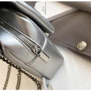 Close-up of silver chain bag showing metallic zipper detail and fine stitching texture