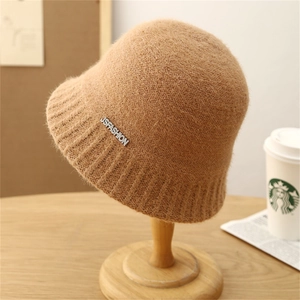 Minimalist crochet striped fisherman hat in khaki with metal logo on a wooden stand