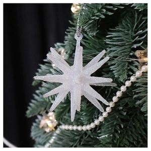 Champagne glitter star ornament hanging on a Christmas tree with pearl chain details