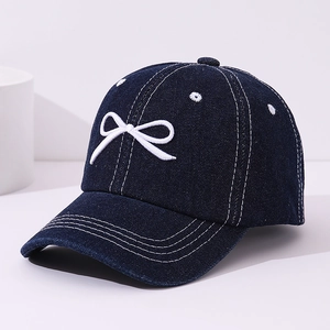 Detail of dark blue denim baseball cap with white bow embroidery texture and stitching