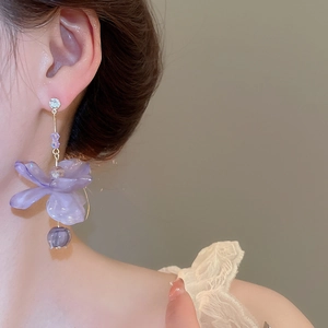 Close-up of purple resin flower drop earrings with sparkling zircon on a female model