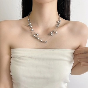 Multi-layer gray pearl necklace with silver chain shown on model in a minimalist style