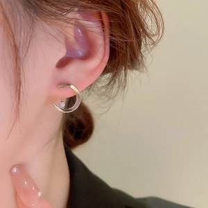 Close-up of geometric moon stud earrings with silver finish and hanging zircon crystal