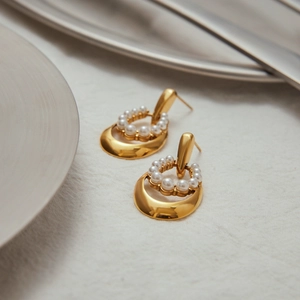Macro detail of 18K gold stainless steel earrings with lustrous white pearls