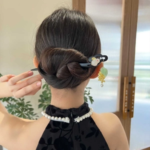 Détail d'un pic à cheveux en bois avec pompon lapin porté en chignon classique