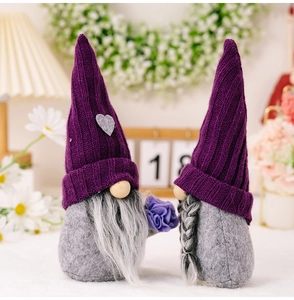 Close-up of two Christmas gnomes with purple knitted hats and heart accents in a cozy setting