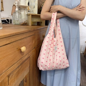 Detailed view of pink canvas tote bag with heart patterns and kakka beauté logo label