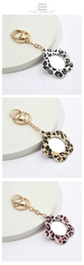 Three leopard print flower mirrors with gold keychains in black, brown, and pink