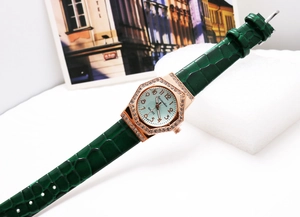 Detailed macro of the rose gold octagonal quartz watch with green faux-leather strap