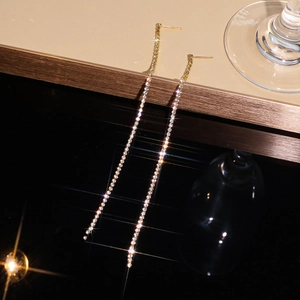 Close-up of elegant long gold tassel earrings with sparkling white rhinestones inlay