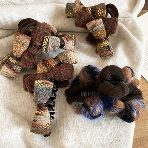 Detail showing various textured tweed bow hair claws in brown and blue colors on knit fabric