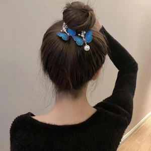 Dettaglio fermaglio per capelli a farfalla blu con strass e perla su capelli intrecciati