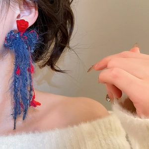 Dettaglio di lunghi orecchini a nappa blu con fiori in resina rossa su modella