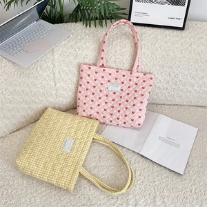 Close-up of quilted heart pattern and plaid tote bags on a soft plush white background