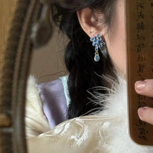 Detailed close-up of blue flower earrings with water-drop charms and silver needles