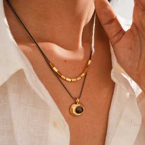 Detail of 18k gold plated double layered necklace with tiger eye stone pendant on model