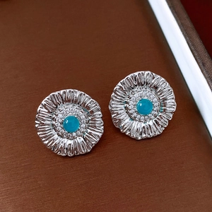 Macro detail of silver vintage flower earrings with blue gemstone and zircon inlay