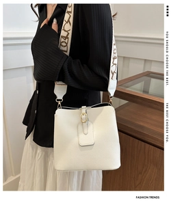 Detail of white lychee leather bucket bag featuring a beige jacquard wide strap