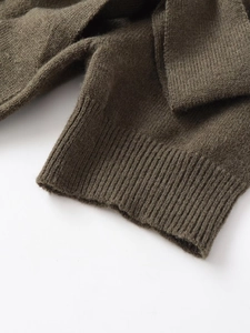Gros plan du haut en maille vert olive avec poignets côtelés fins et texture de tissu noble