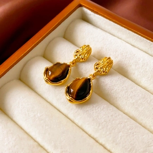 Detail of vintage gold-plated teardrop earrings with tiger eye stone on jewelry box