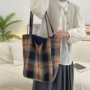 Detail of vintage wool plaid tote bag in navy and orange being held by a model