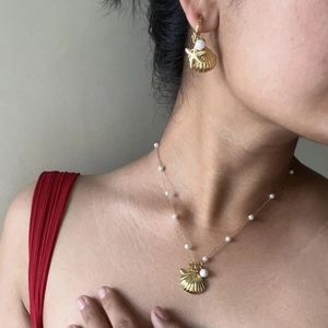 Detail of gold shell and starfish jewelry set with pearls on a female model