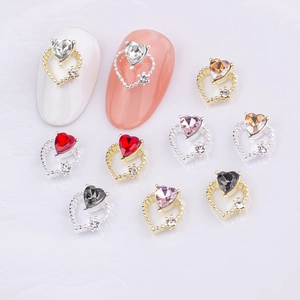 Close-up of hollow heart nail charms with colorful crystals and gold metal base
