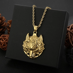 Makroaufnahme eines goldenen Wolfskopf-Anhängers an einer Kordelkette auf einer Box
