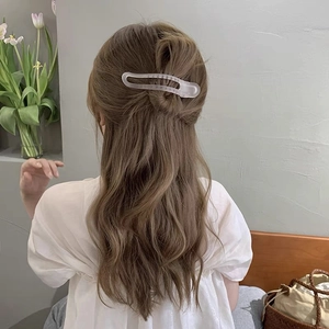 Close-up of a matte translucent duckbill hair clip worn in a half-up hairstyle