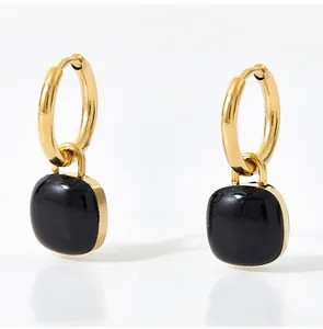 Detailed view of square black enamel pendants on gold stainless steel hoop earrings